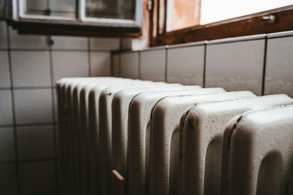 Radiador blanco bajo una ventana de madera